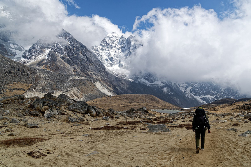 hiker against high mountains partly in couds