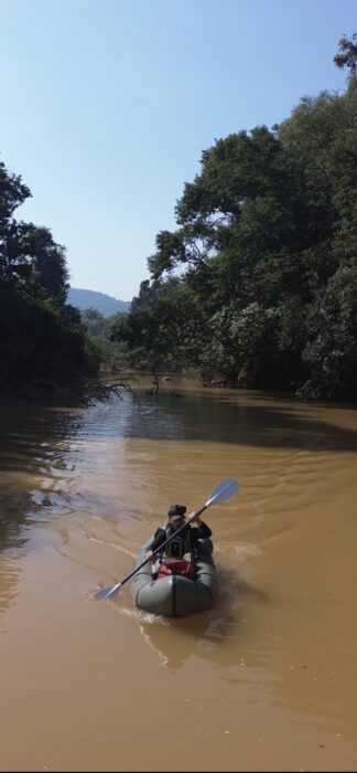 a man paddles a boat along a muddy river