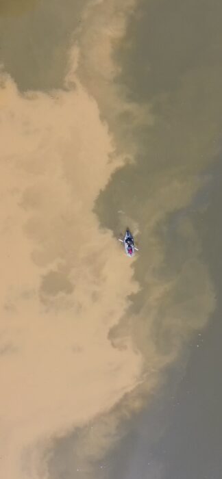 a man paddles a boat on a muddy river