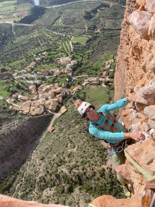 Jeff Wright climbing on conglomerate, the red roofs of a Spanish village down below