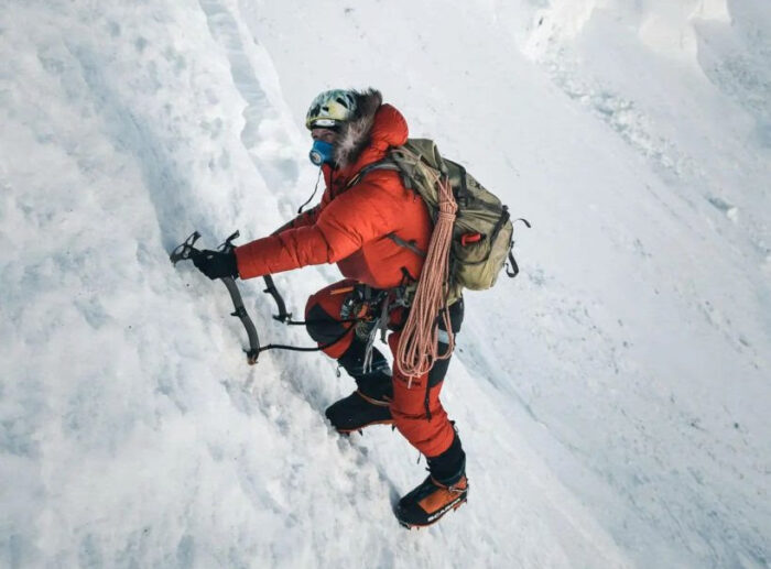 Kobusch on a steep hard snow/ice ramp, dressed in full altitude suit with fur-rimmed hood