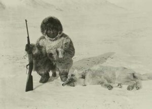 Inuit man in furs beside dead wolf