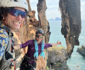 The climbers under an overhanginf rock formation by the sea