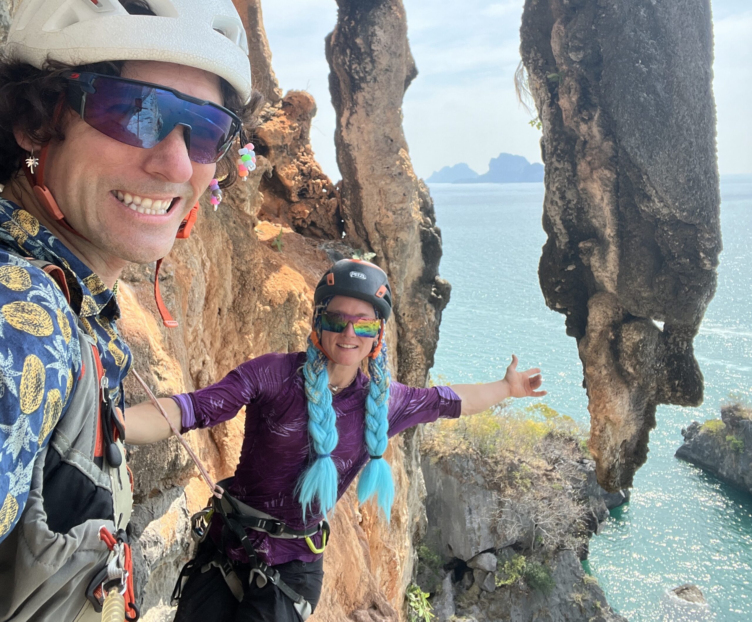 The climbers under an overhanginf rock formation by the sea