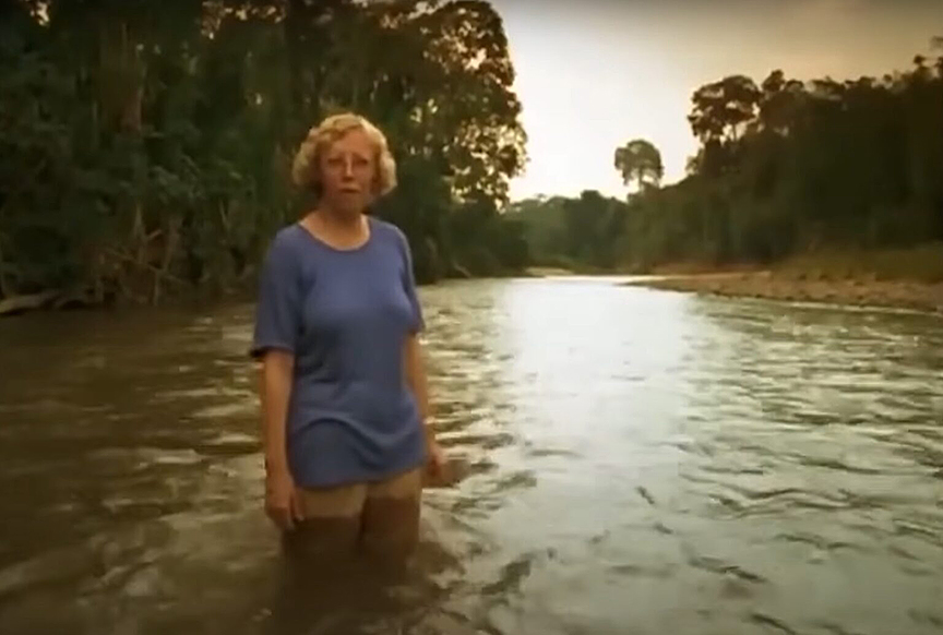 Middle-aged blonde woman standing in jungle river