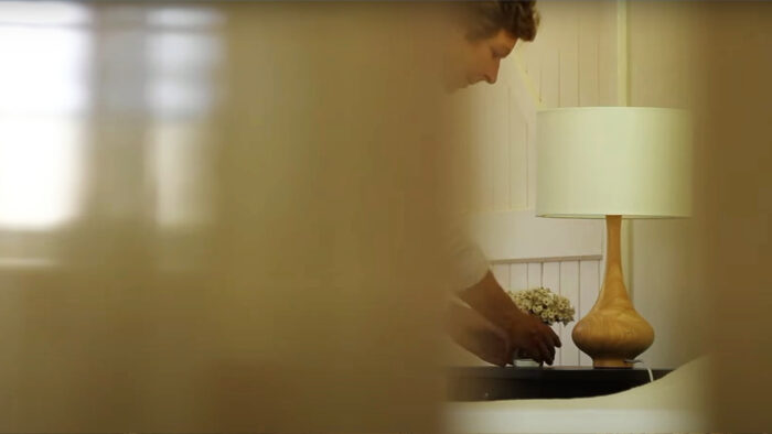 a woman places flowers on a nightstand