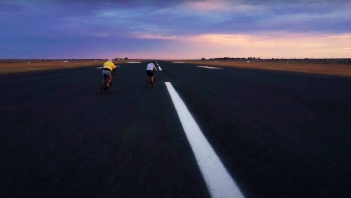 two people ride bicycles on an empty runway