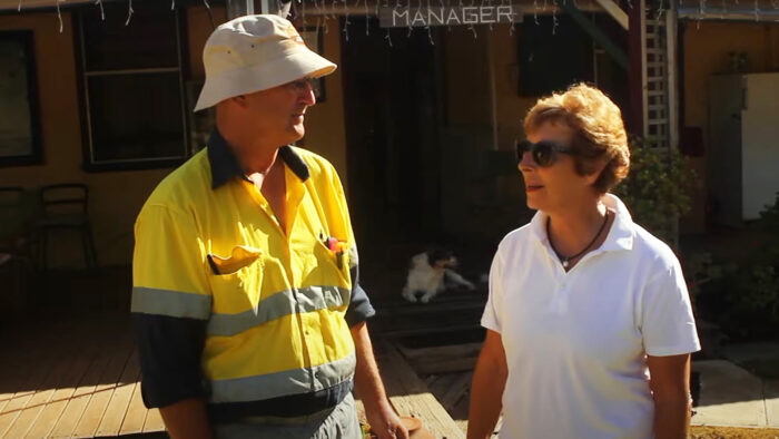 a man and a woman stand outside looking at each other