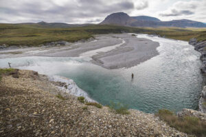 fisherman standing in wilderness river