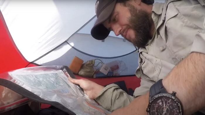 a man reads a map in a tent