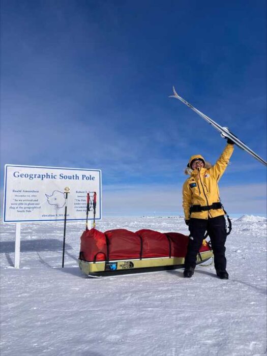 a woman holds up her skis at the south pole