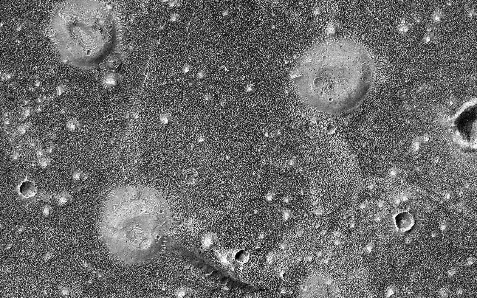 A grayscale photo of mounds with craters on top.