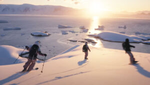 three skiers at sunset