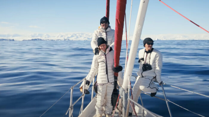 three people stand at the mast of a ship