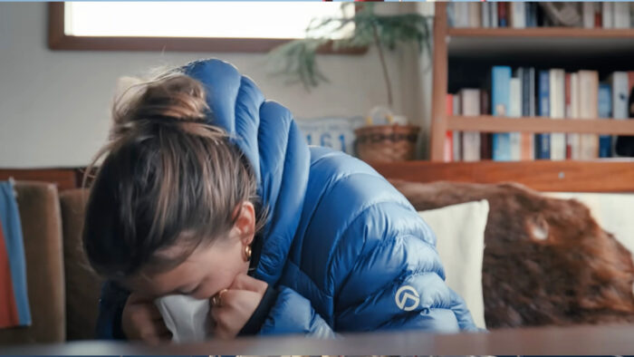 a young woman vomits into a bag