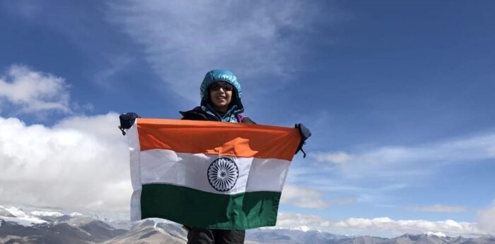 A Girl hlds an indian flag on the summit of Aconcagua.