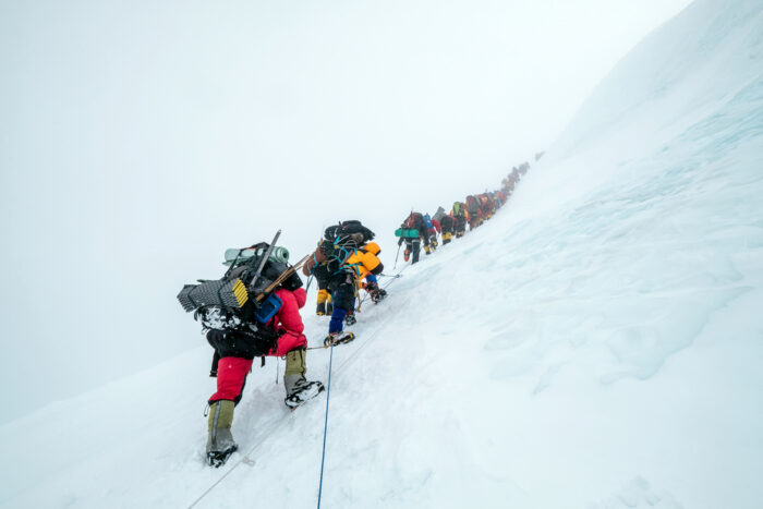 climbers in line clipped to ropes in the fog