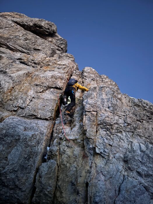 A climber soloing a rock section on a mountain face