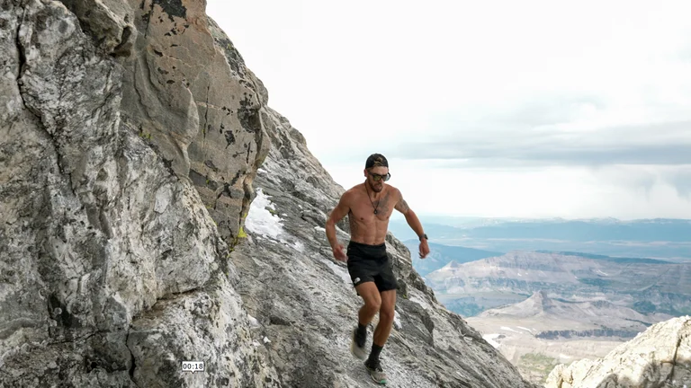 A man runs down a steep rocky area.