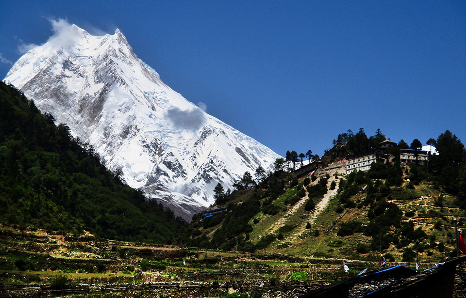 bright snowy peak with dark village foreground