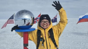 a woman stands next to the south pole