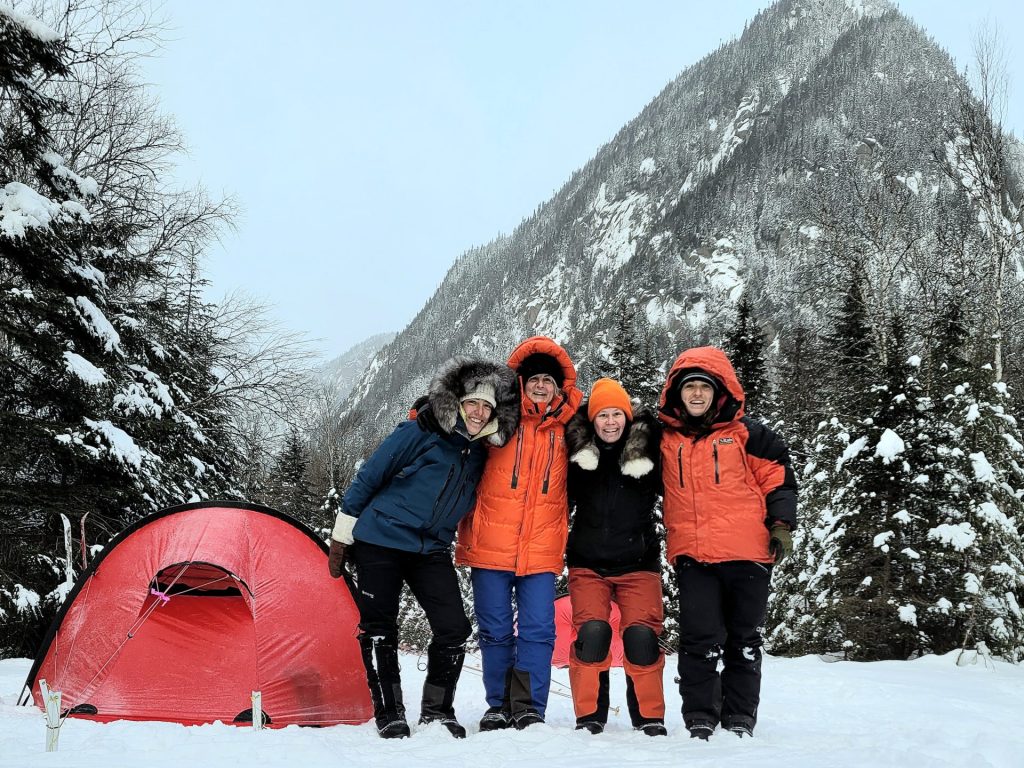 four women in winter beside a red tent