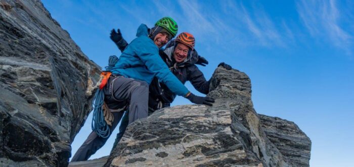 Para pendaki dengan pembantu di puncak berbatu. 