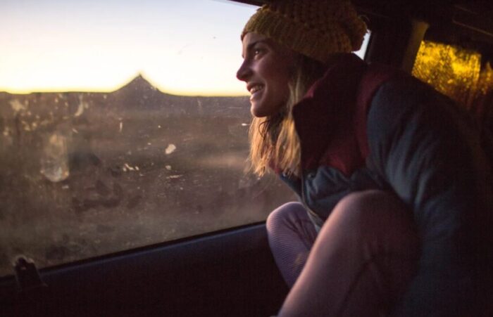 Jenny Abbeg looks at the sunset on desert landscape from a van's window.