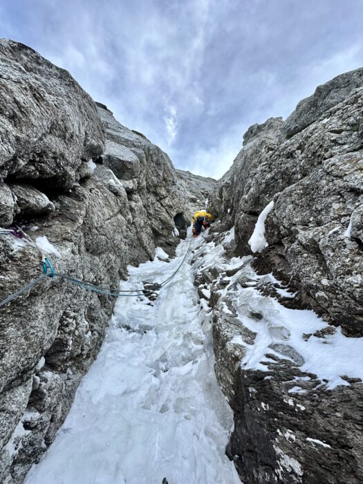 A climber up an ice gully in a mixed face in winter