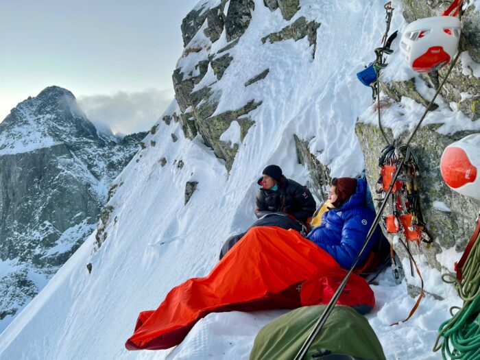 CLimbers vibouaquing on a narrow sledge cut in a steep snow ramp