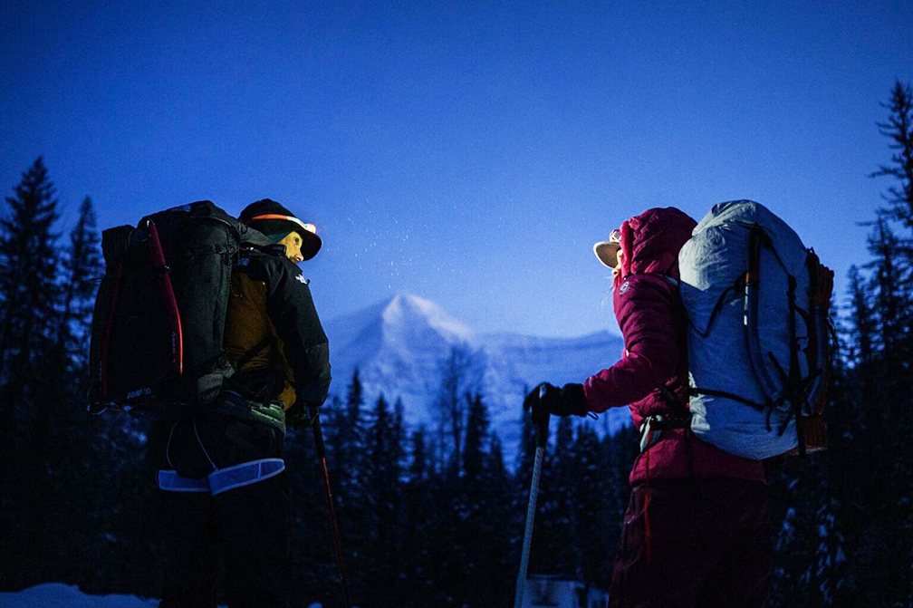 The climbers at dawn, with headlamps on, approaching a mountain.