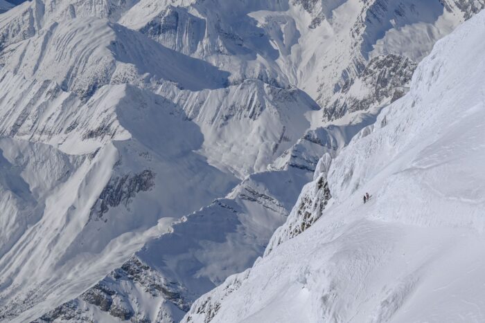 Two skiers on the steep south face of Mt. Robson, seen from a drone