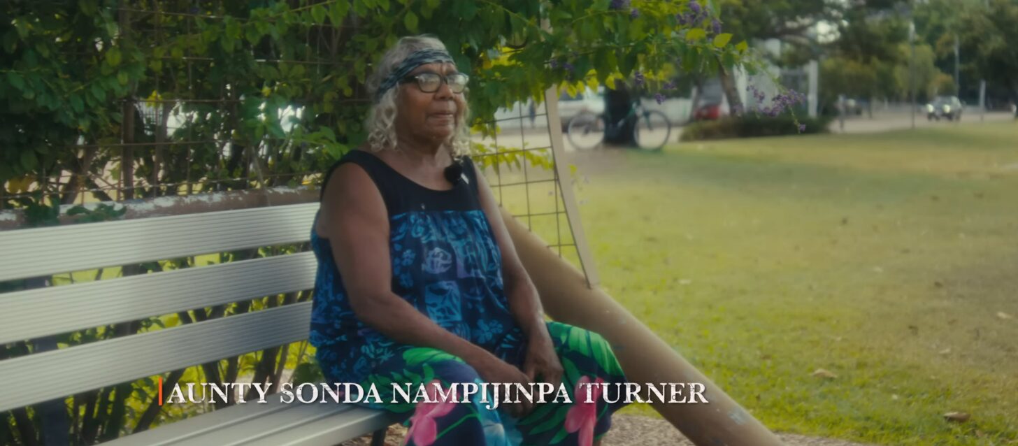 An elderly woman sitting on a bench.