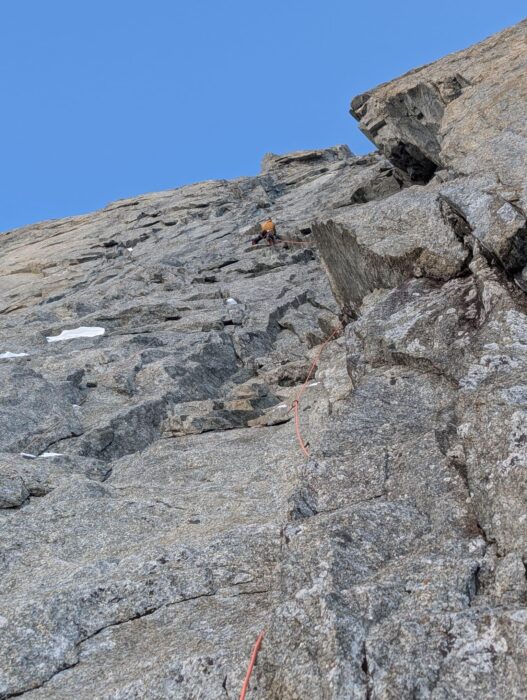 A climber progressing up a granite face with dry tooling technics