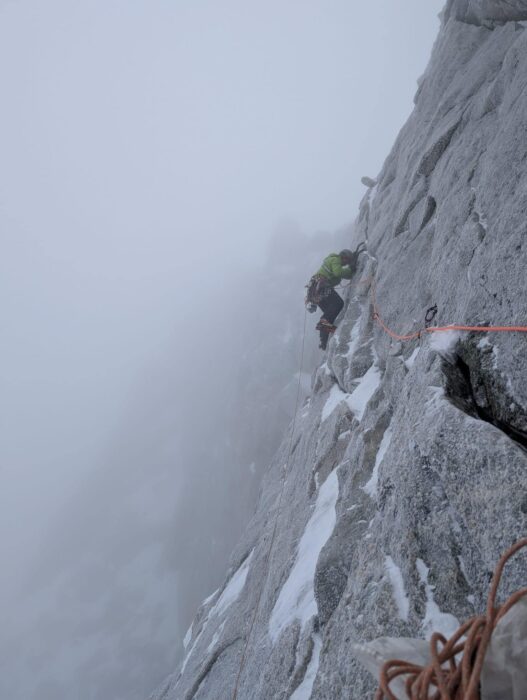 Climbers at a traverse on a granite wall wrapped in fog