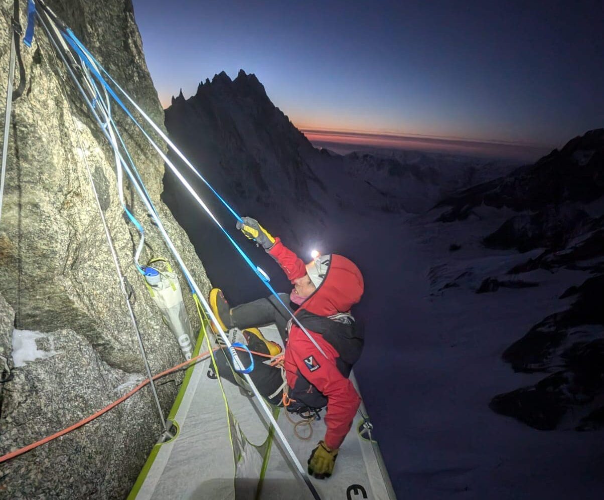 Climber looking up at sunrising from a portaledge