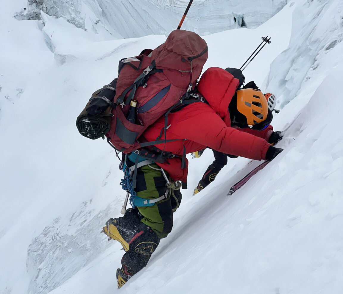 A climber on a steep snow slope, his feet sinking