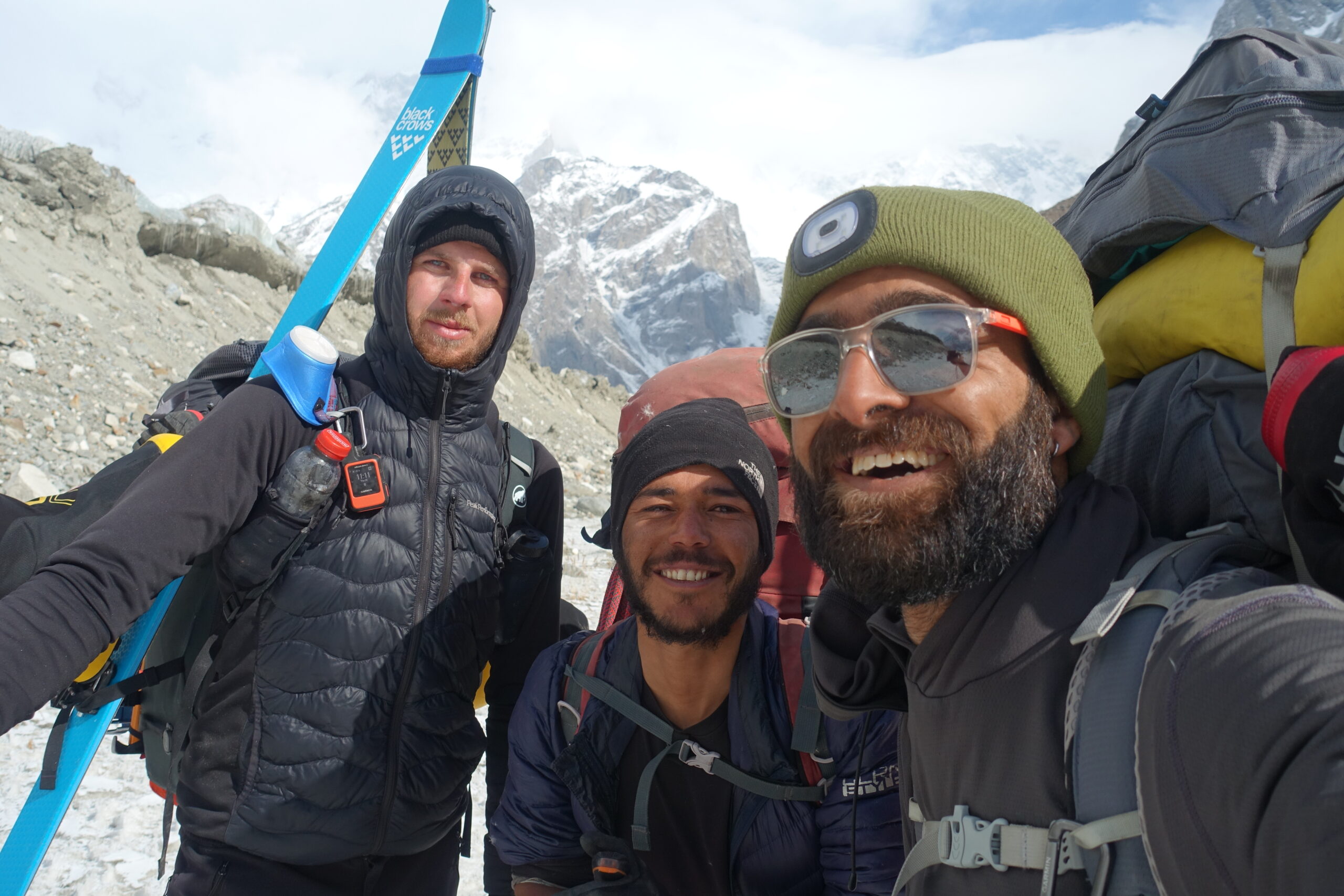 Ueltschi with skis on his backpack and the two pakistani climbers take a selfie