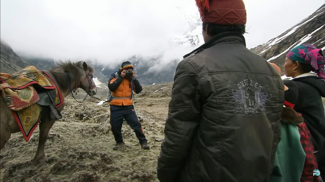 A man taking a picture of several people, seen from behind.