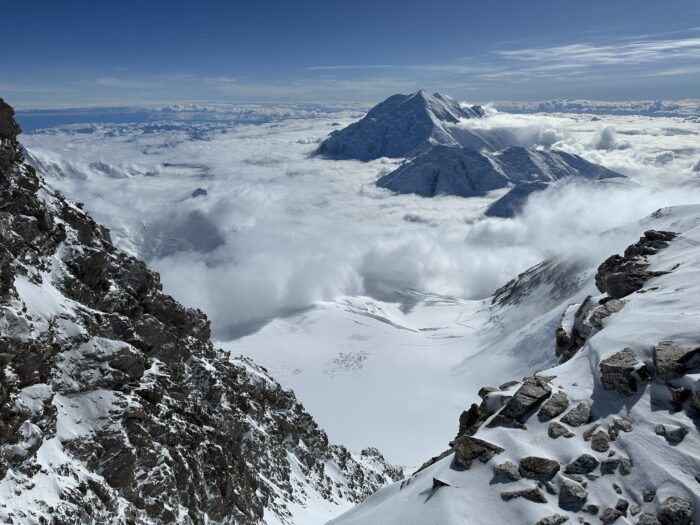 tiny tents on a huge snow plateau as seen from an upper col on Denali