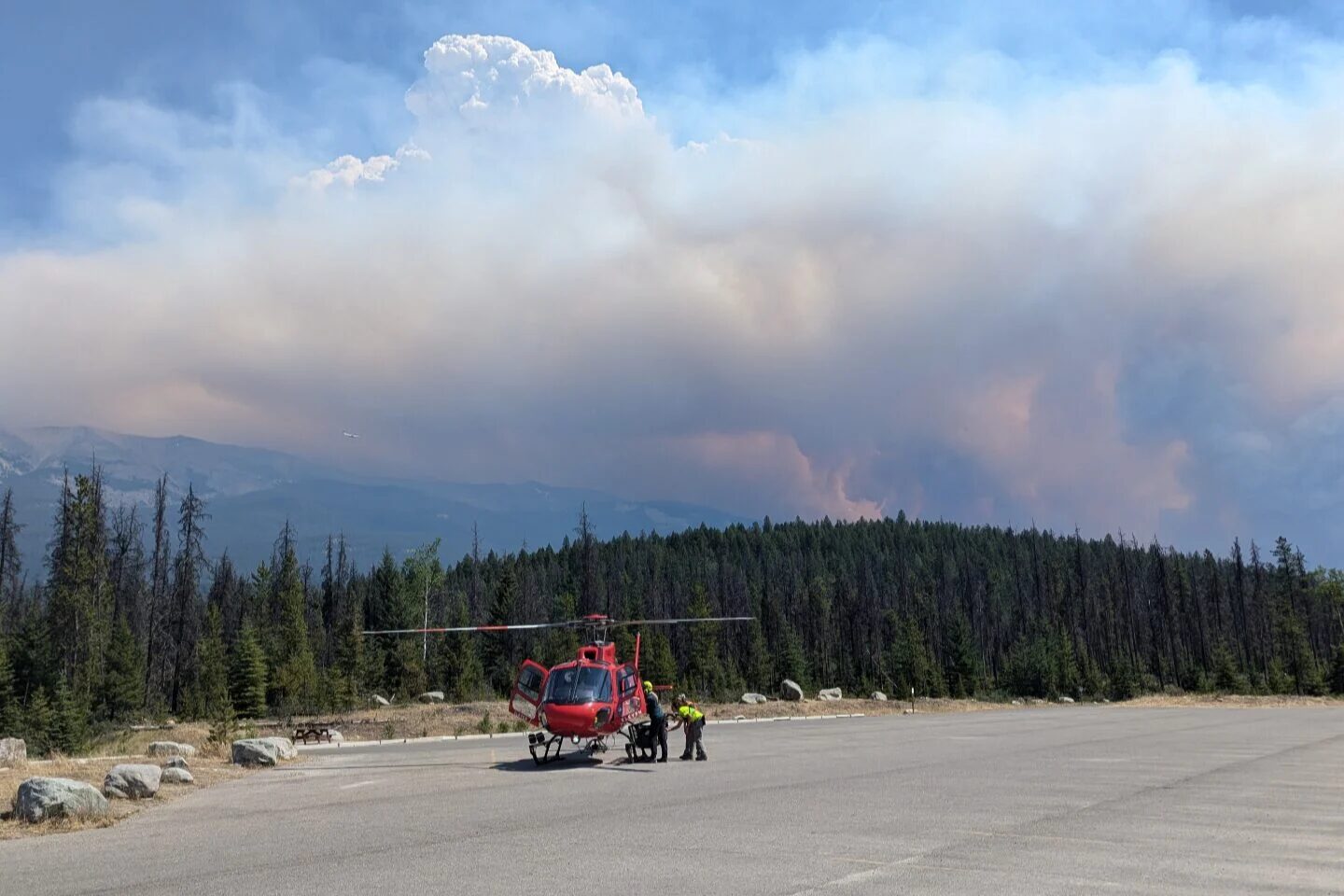 A helicopter, with forest and smokey sky.