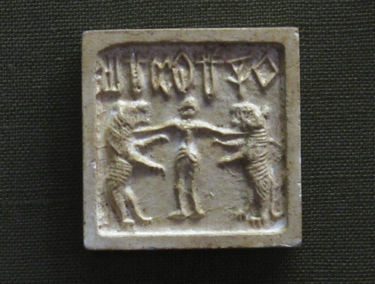 a tablet showing a man with two tigers below a series of sigils