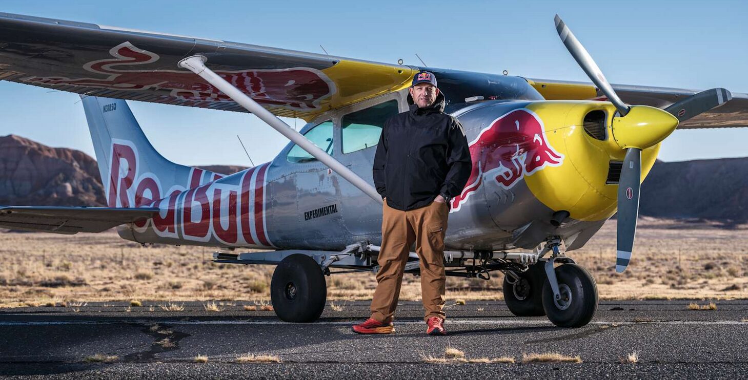 A man standing next to a plane in the desert.