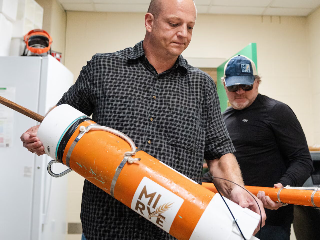 A man holding a big orange tube.