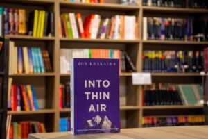 A book shoowing the cover, in front of a bookshelf