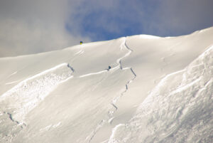 two skiers trigger a slab avalanche on a snow slope