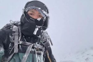 A young man bundled up in a snowy white void