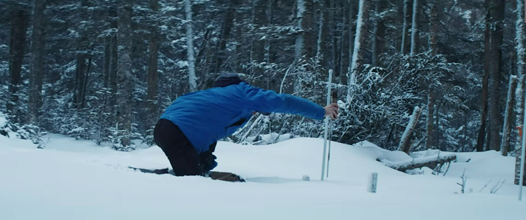 A man checking a device which emerges from the snow.