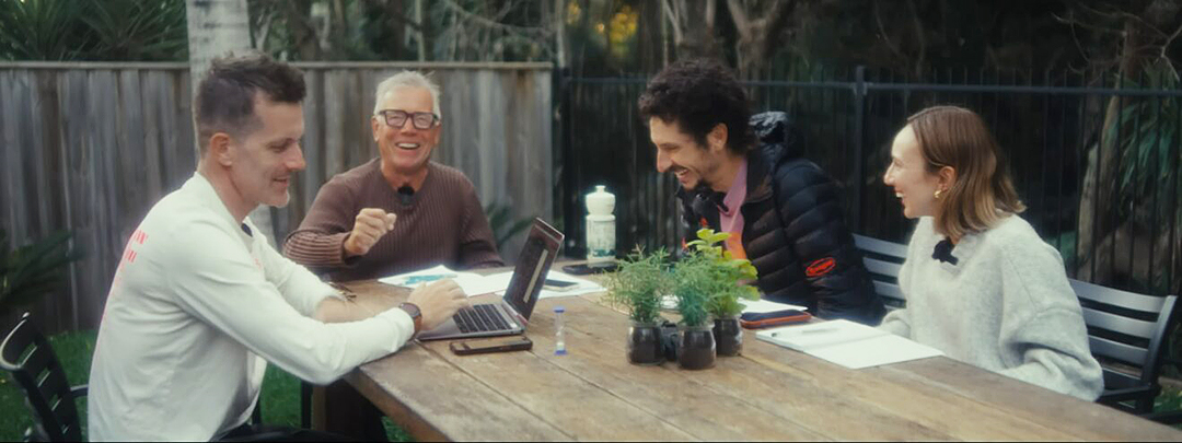 Four people around a table, smiling.