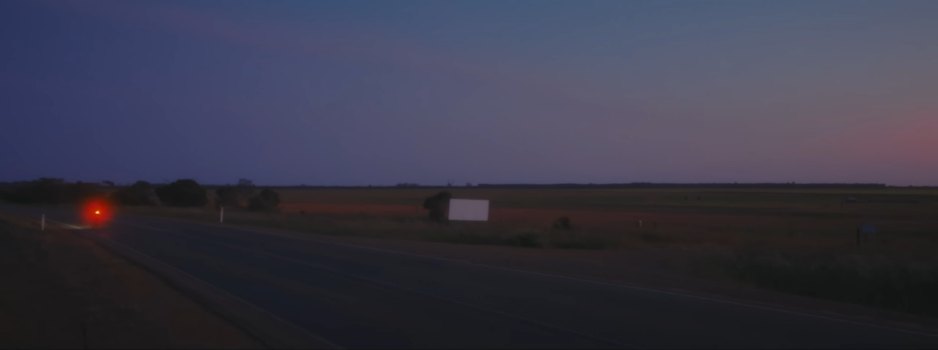 The red light of a bike in a dusky purple twilight.